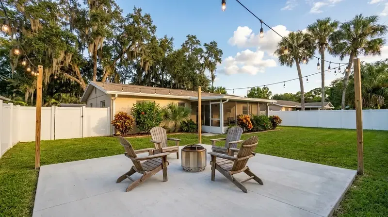 Concrete patio with Adirondack chairs around a fire pit and string lights, patio work in Port Orange, FL